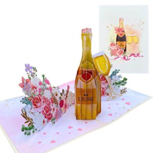 Carte de vœux pop-up 3D ouverte avec une bouteille de champagne, une flûte et des bouquets, à côté de sa couverture ivoire