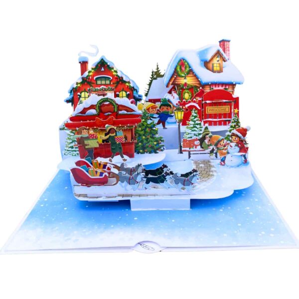 Full view of the open 3D pop-up card showing a Christmas village with characters and a sled.