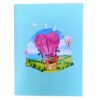 Closed 3D pop-up love card: blue cover showing the heart balloon over green hills