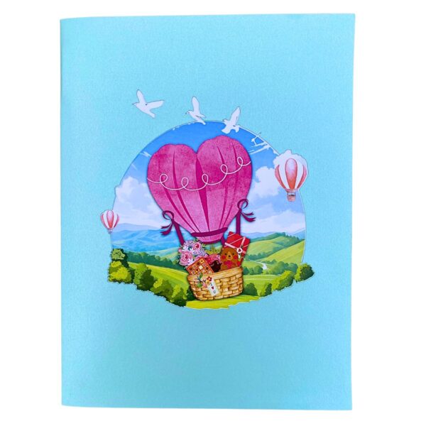 Closed 3D pop-up love card: blue cover showing the heart balloon over green hills
