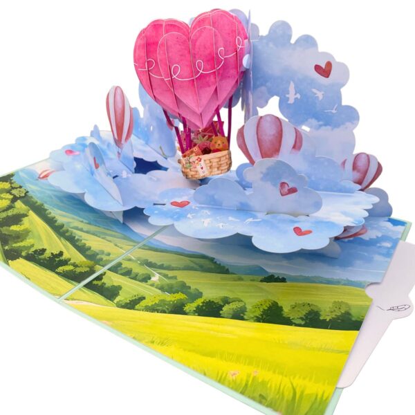 Angled view of the open 3D pop-up love card with a pink heart-shaped hot air balloon above clouds